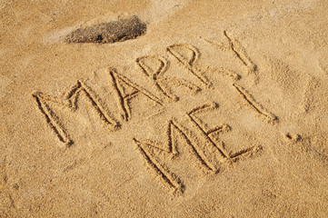 The words Marry Me written in the sand on the beach