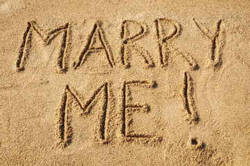 The words Marry Me written in the sand on the beach