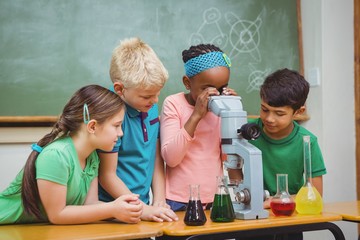 Students using science beakers and a microscope