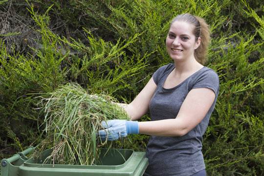 Girl with grass near green bin