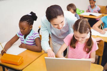 Teacher using laptop with pupil