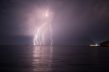 Naklejka na ściany i meble Spectacular lightnings striking the surface Aegean Sea