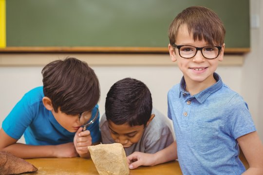 Pupils looking at rock with magnifying glass