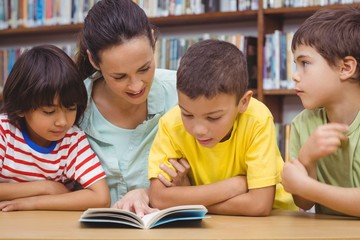 Fototapeta na wymiar Pupils and teacher reading book in library