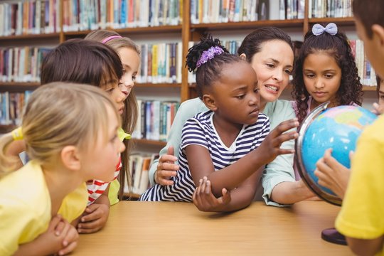 Pupils and teacher looking at globe in library