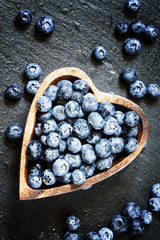 Fresh blueberries with water droplets in a wooden bowl in the sh