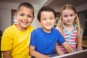 Cute pupils in computer class using laptop