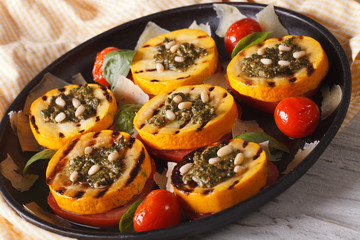 grilled zucchini and tomatoes with pesto, cheese and nuts closeup. Horizontal
