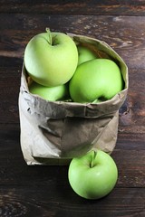 Äpfel der Sorte Delbar in einer Papiertüte auf Holzhintergrund