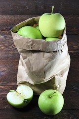 Äpfel der Sorte Delbar in einer Papiertüte auf Holzhintergrund