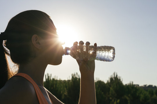 Backlighting of a runner woman drinking water