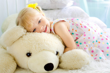 little girl embracing big white teddy bear