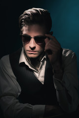 Handsome retro fashion man with vintage shades in waistcoat and scarf.