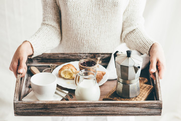 Woman serving breakfast on wooden tray. Window light