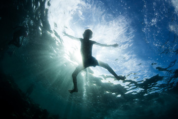 Fototapeta premium Silhouetted Child at Play in Tropical Pacific Ocean