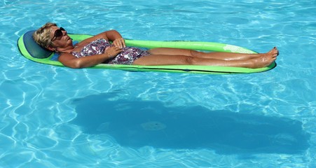 An english Lady relaxing in a swimming pool while on holiday