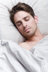 Fototapeta na wymiar Young handsome man sleeping in bed