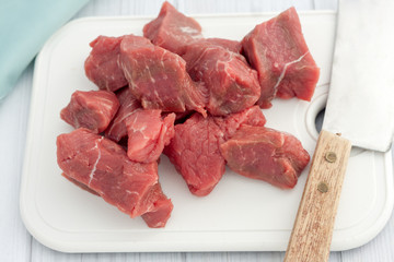 big pieces of  of raw beef on white choping board