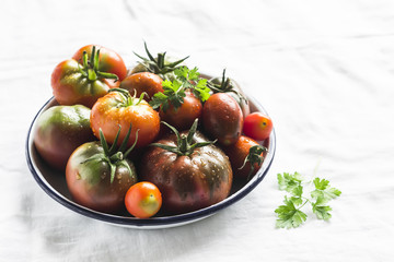 fresh tomatoes on a white enamel plate on a light surface