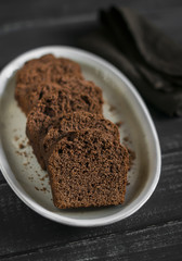 pieces of chocolate cake on the oval dish on dark wooden background