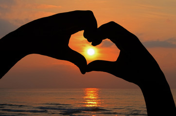 Sunrise in Hand Heart Frame on Beach View.