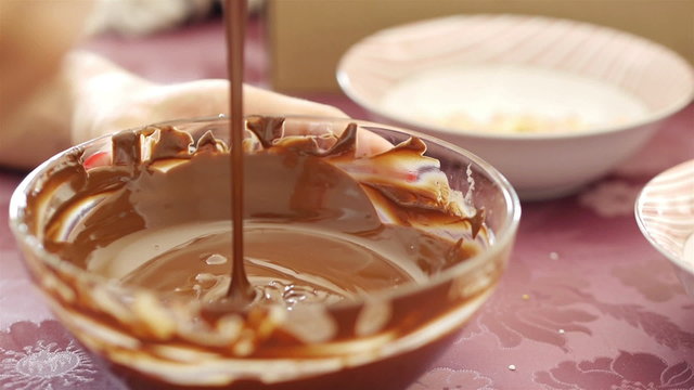 Woman melting hot chocolate sauce for dessert in bowl close up