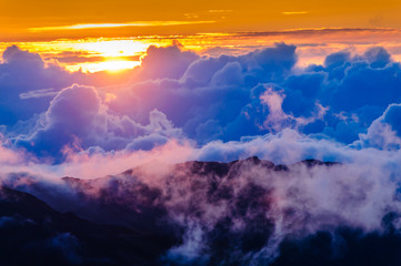Obraz premium Sunrise over clouds and distant mountains from Haleakala Crater.