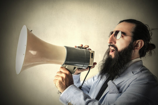 Long-bearded businessman screaming into a megaphone