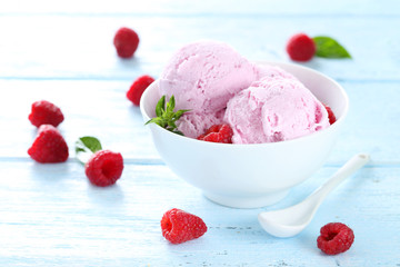Ice cream in bowl with raspberries on blue wooden background