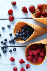 Waffle cones with berries on wooden table