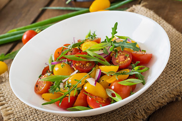 Salad of fresh cherry tomatoes with onion and arugula