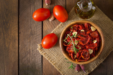 Sun-dried tomatoes with herbs and garlic in wooden bowl