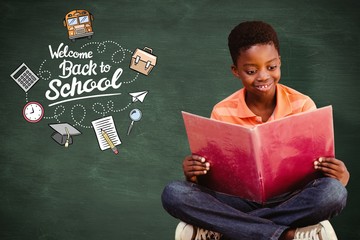 Composite image of cute boy reading book in library