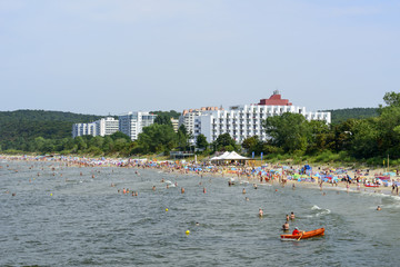 Tourists enjoy the sunny weather and relaxing on the Baltic sea beach in Miedzyzdroje, Poland.