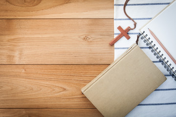 wooden Christian cross necklace on holy Bible on wood table