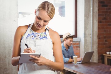 Smiling blonde waitress taking order in front of customer