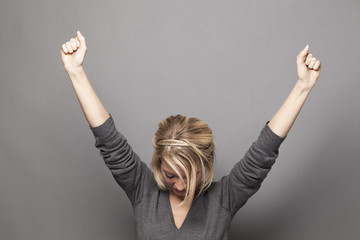 humble 20s blonde woman raising hands for victory - obrazy, fototapety, plakaty