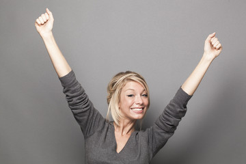beautiful 20s blonde woman raising hands for victory