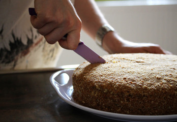 Woman is cutting honey cake with a knife
