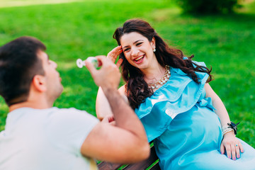 Beautiful pregnant couple relaxing outside in the park.