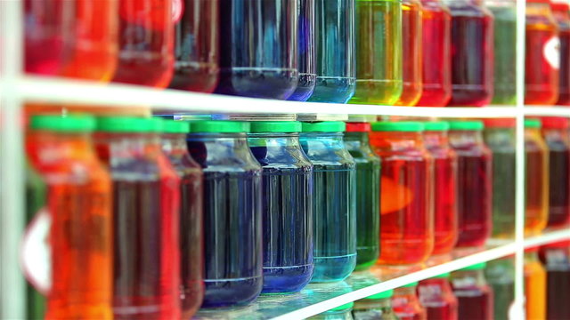 Lots of glass jars with colorful fruit compote in the window of a grocery store.