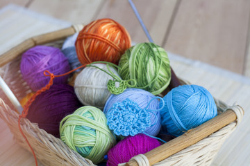 Colorful clews and crochet hook on wooden background