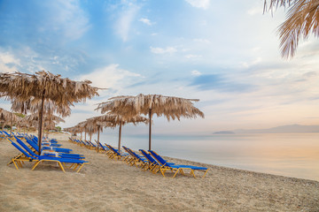Vivid sunrise on a beautiful sandy beach with sunshade