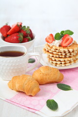 Tea with croissants and fresh strawberries on the table