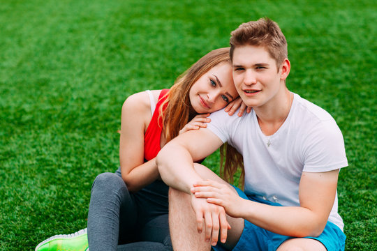 Young Athletic Couple Sitting On The Grass