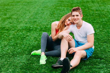 Young athletic couple sitting on the grass