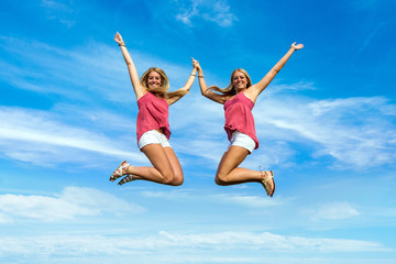Fototapeta na wymiar two pretty girls jumping in park holding hands