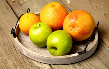 Apples and oranges on old wooden background