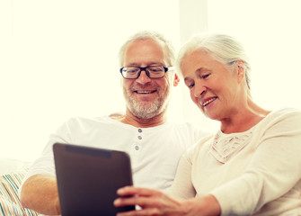 happy senior couple with tablet pc at home