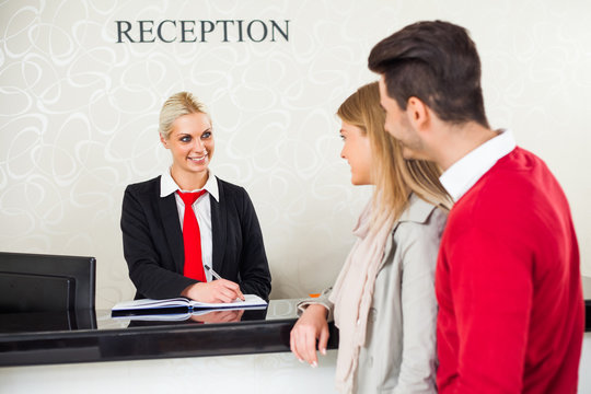 Young Couple Check In At Hotel Reception